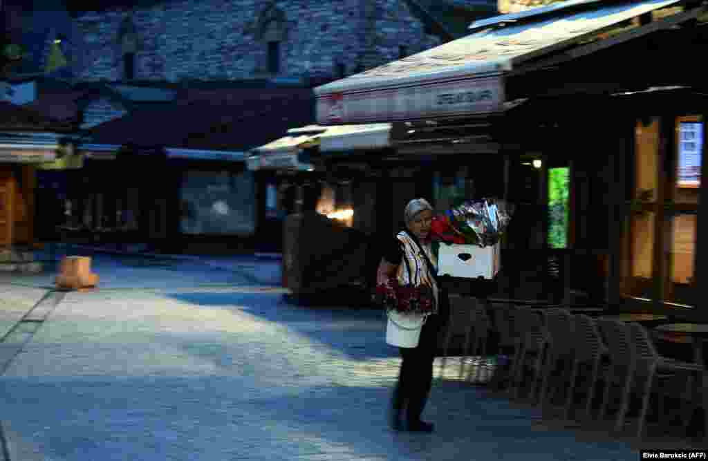 Уличный торговец несет ящики с цветами для продажи после утренней молитвы в окрестностях мечети Гази Хусрев-бег в Сараево, Босния и Герцеговина