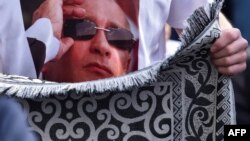 Президент РФ В. Путин "выглядывает" из-за мусульманского молитвенного коврика