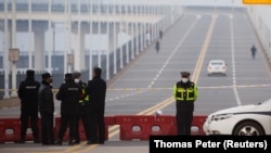 Police stand at a roadblock at a bridge crossing the Yangtze River to Hubei province in Jiujiang, Jiangxi province, China, as the country is hit by an outbreak of a new coronavirus, January 30, 2020