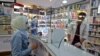 People wearing protective masks shop at a pharmacy in the capital Tehran, February 24, 2020