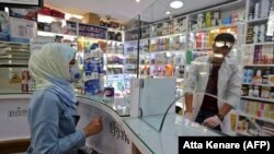 People wearing protective masks shop at a pharmacy in the capital Tehran, February 24, 2020