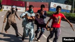 Supporters of Tahir-ul Qadri, Sufi cleric and leader of political party Pakistan Awami Tehreek (PAT), carry an injured fellow protester during the Revolution March in Islamabad on August 31, 2014.