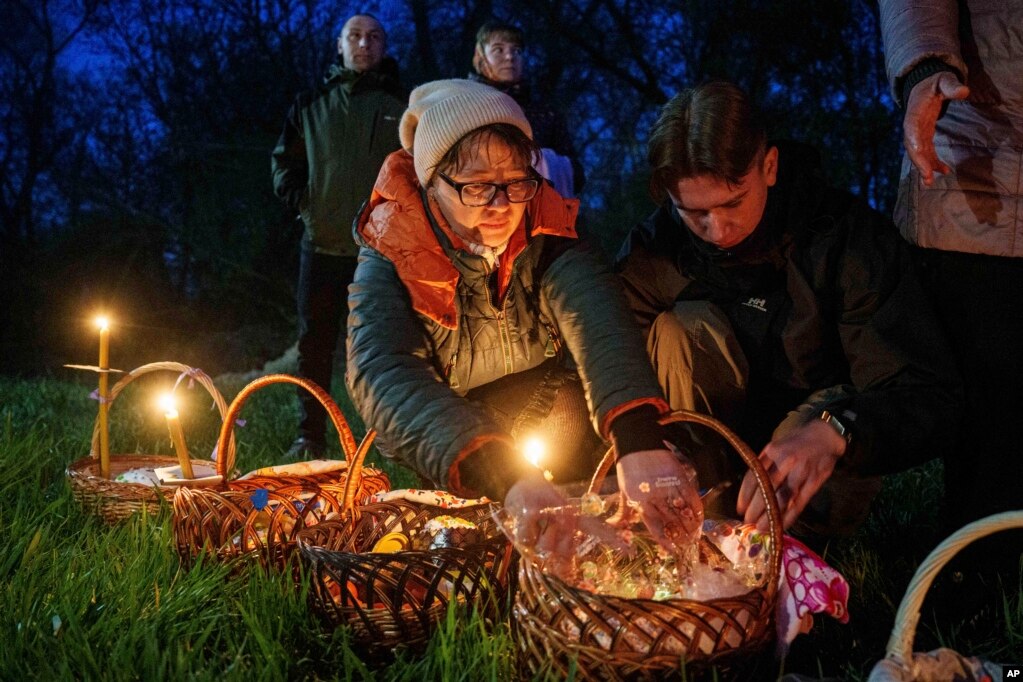 Disa persona përgatisin shportat e Pashkëve për t'u bekuar para një kishe të shkatërruar gjatë luftës në Lukashivka, në Ukrainë. 20 prill 2025. 
