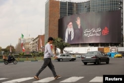 Перехожі біля білборда з зображенням покійного верховного лідера Ірану аятоли Алі Хаменеї на вулиці після його смерті внаслідок авіаударів Ізраїлю та США в суботу в Тегерані, Іран, 2 березня 2026 року