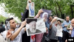 Iranian campaign activists distribute electoral posters of presidential candidates Rouhani and Raiesi after Friday prayers in Tehran, May 12, 2017