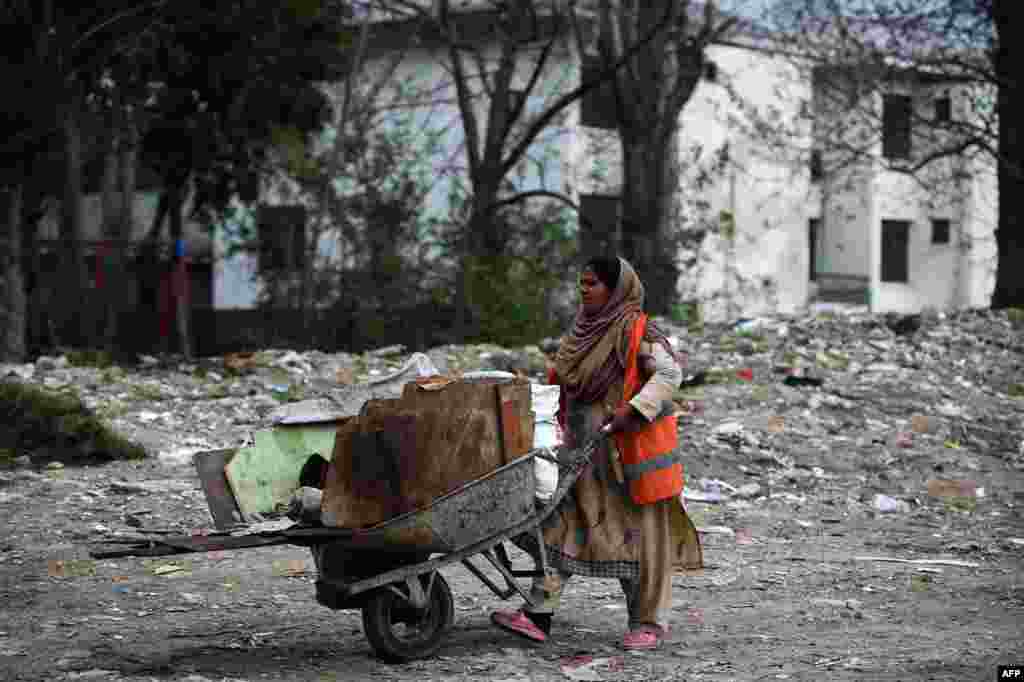 A Pakistani female worker pushes a trolley of material along a street in Islamabad. (AFP/Farooq Naeem)