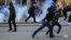 Protesters run away from tear gas fired by police officers during clashes at the Pristina on February 7.