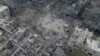 Palestinezët ecin afër rrënojave të ndërtesave të shkatërruara nga sulmet ajrore izraelite në kampin e refugjatëve Nuseirat në Rripin e Gazës. 29 tetor 2023. 