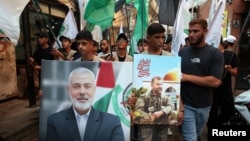 Palestinians carry pictures of late Hamas deputy leader Saleh al-Arouri and leader Ismail Haniyeh, who was assassinated in Iran, during a march to condemn Haniyeh's killing, at the Burj al-Barajneh Palestinian refugee camp in Beirut on July 31.