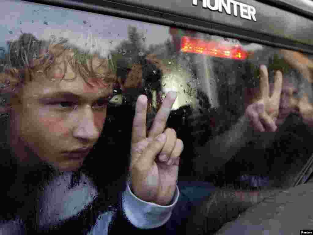 Men gesture as they sit in a police car after being detained by Belarusian authorities in central Minsk on November 29. (REUTERS/Vasily Fedosenko)