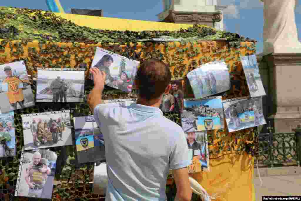 Відвідувач ярмарку роздивляється фото бійців добровольчого батальйону &laquo;Айдар&raquo;