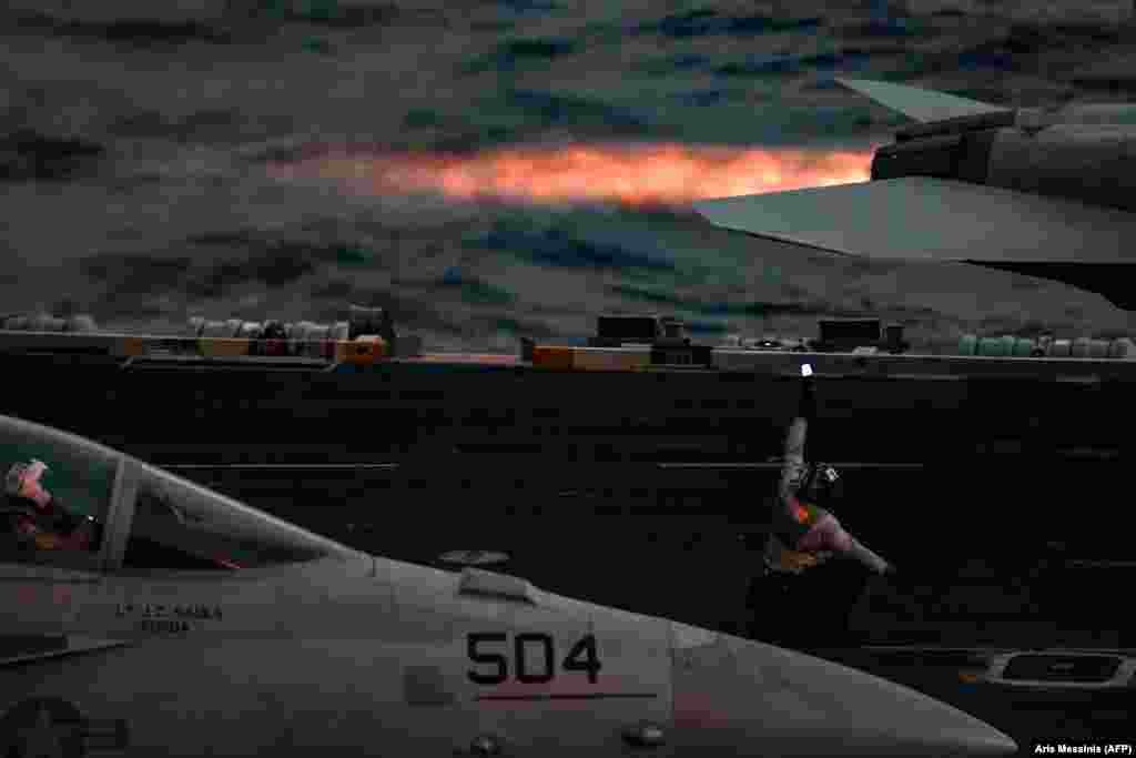 A crew member of the U.S. aircraft carrier Harry S. Truman gestures as the pilot of an F/A-18 Hornet fighter jet waits to take off on the eastern Mediterranean Sea. (AFP/Aris Messinis)