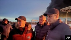 Saratov regional Governor Roman Busargin (right) speaks to firefighters and rescuers at an industrial site that was targeted in a Ukrainian drone attack on January 8. 