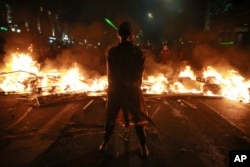 Demonstrant privind la o baricadă în flăcări, în centrul Tbilisi, la 3 decembrie.