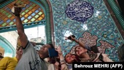 Iranians take a selfie as they wait in a queue to vote for the presidential elections at a polling station in Tehran on May 19, 2017. 