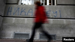 A man walks past graffiti in the Serbian capital, Belgrade, that reads "Never in EU."