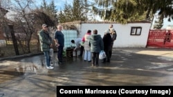 Locuitorii din Curtea de Argeș așteaptă să ia apă potabilă din canistrele instalate de Primărie.