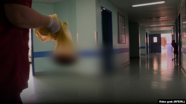 Një infermiere në Klinikën e Gjinekologjisë bart një qese me placentë.