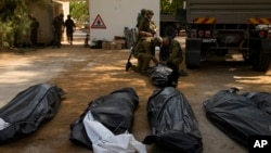 Izraeli katonák szállítják el a holttesteket a Kfar Aza kibucból 2023. október 10-én