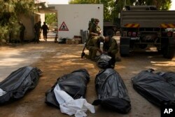 Cadavrele celor uciși de Hamas în atacul surpriză din 7 octombrie, în urma unei infiltrări în masă, sunt fotografiate de jurnaliștii străini în kibbutzul Kfar Aza din sudul Israelului, 10 octombrie 2023.