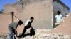 Boys remove rubble from the site of a mortar attack in Al-Najaf on May 23 (file photo)