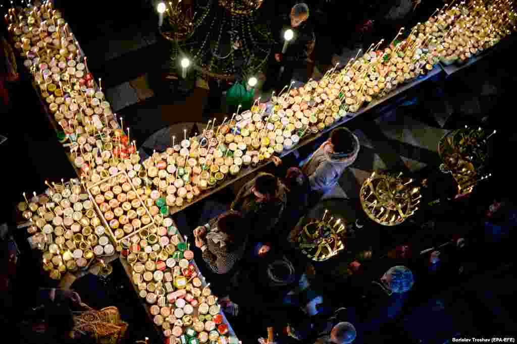 Believers attend a ceremony marking the day of St. Haralampi, protector of beekeepers, around a cross-shaped platform covered with candles placed in jars of honey at the Church of the Blessed Virgin in Blagoevgrad, Bulgraia, on February 10. (epa-EFE/Borislav Troshev)