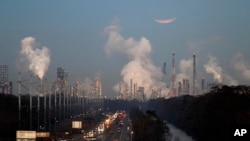 A supermoon, undergoes an eclipse as it sets beyond gas refineries, at sunrise in St. Charles Parish, La., Wednesday, Jan. 31, 2018.