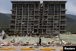 Njerëzit inspektojnë rrënojat e një ndërtese të shembur pasi tërmetet goditën vendin, në La Guaira, Venezuelë, 25 qershor 2026.