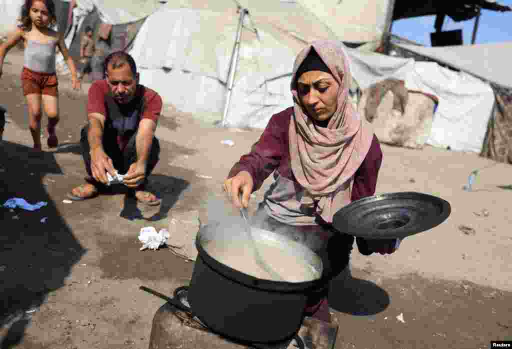 Žena kuha dok raseljeni Palestinci koji nisu primili humanitarnu pomoć preživljavaju na ostacima hrane, usred krize gladi, u Gazi, 28. jula 2025.