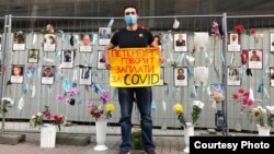 A medical worker pickets for COVID hazard payments in front of a St. Petersburg memorial for colleagues who have died of the disease.