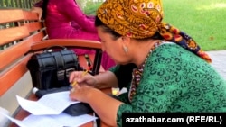 Turkmenistan. weekly photos 37th week. women are writing formal letter and sitting on bank