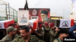 Anëtarë të Forcave të Mobilizimit Popullor mbajnë mbetjet mortore të luftëtarëve të vrarë në bombardimet e dyshuara amerikane në Bagdad, në prill.