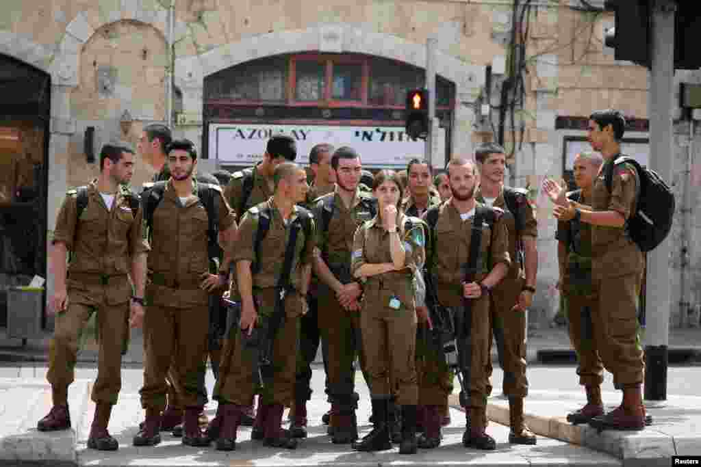 Soldații israelieni așteaptă să traverseze o stradă după ce Israelul a anulat purtarea obligatorie a măștilor. Jaffa, Israel, 18 aprilie, 2021. REUTERS / Amir Cohen