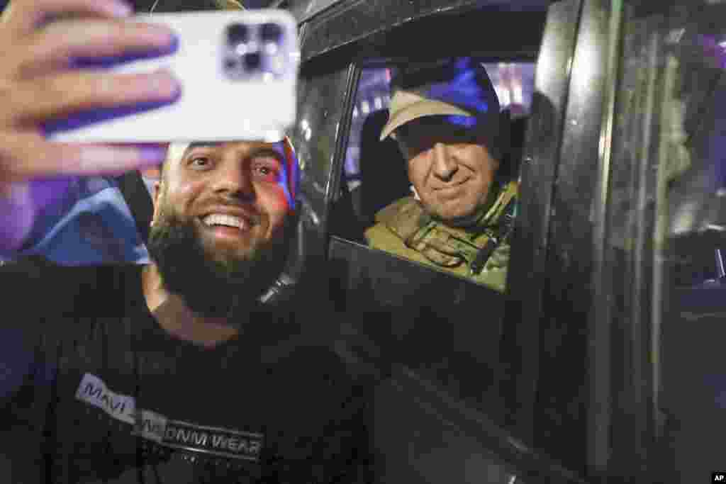 Yevgeny Prigozhin, leader of the Wagner mercenary group, sits inside a military vehicle as a local resident takes a picture with him on a street in Rostov-on-Don, Russia, on June 24. Prigozhin, who sent his fighters to topple the military leaders in Moscow, will leave for Belarus, and a criminal case against him will be dropped as part of a deal to avoid &quot;bloodshed,&quot; the Kremlin said on June 24. &nbsp;