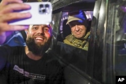 Организатор военного мятежа Евгений Пригожин сидит в военной машине и позирует для селфи с местным жителем на улице Ростова-на-Дону, 24 июня 2023 года