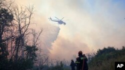Zjarrfikësit duke tentuar të shuajnë flakët në një pyll, në periferinë veriperëndimore të Kryonerit, në Athinë, Greqi, të shtunën, më 26 korrik 2025. 