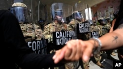 Demonstranti se rukuju ispred pripadnika Kalifornijske nacionalne garde u Los Angelesu, Kalifornija, SAD, 9. juna 2025.