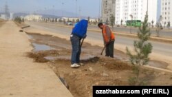 Parahat-8 etrapçasynda ýollaryň gyrasyny abatlaýan işçiler.