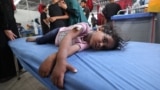 Gaza - EDITORS NOTE: Graphic content / A woman and a child cry as a little girl lies on a hospital bed waiting for first aid treatment at Al-Awda Hospital at the Nuseirat refugee camp in the central Gaza Strip, May 19, 2025.