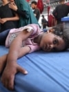 Gaza - EDITORS NOTE: Graphic content / A woman and a child cry as a little girl lies on a hospital bed waiting for first aid treatment at Al-Awda Hospital at the Nuseirat refugee camp in the central Gaza Strip, May 19, 2025.