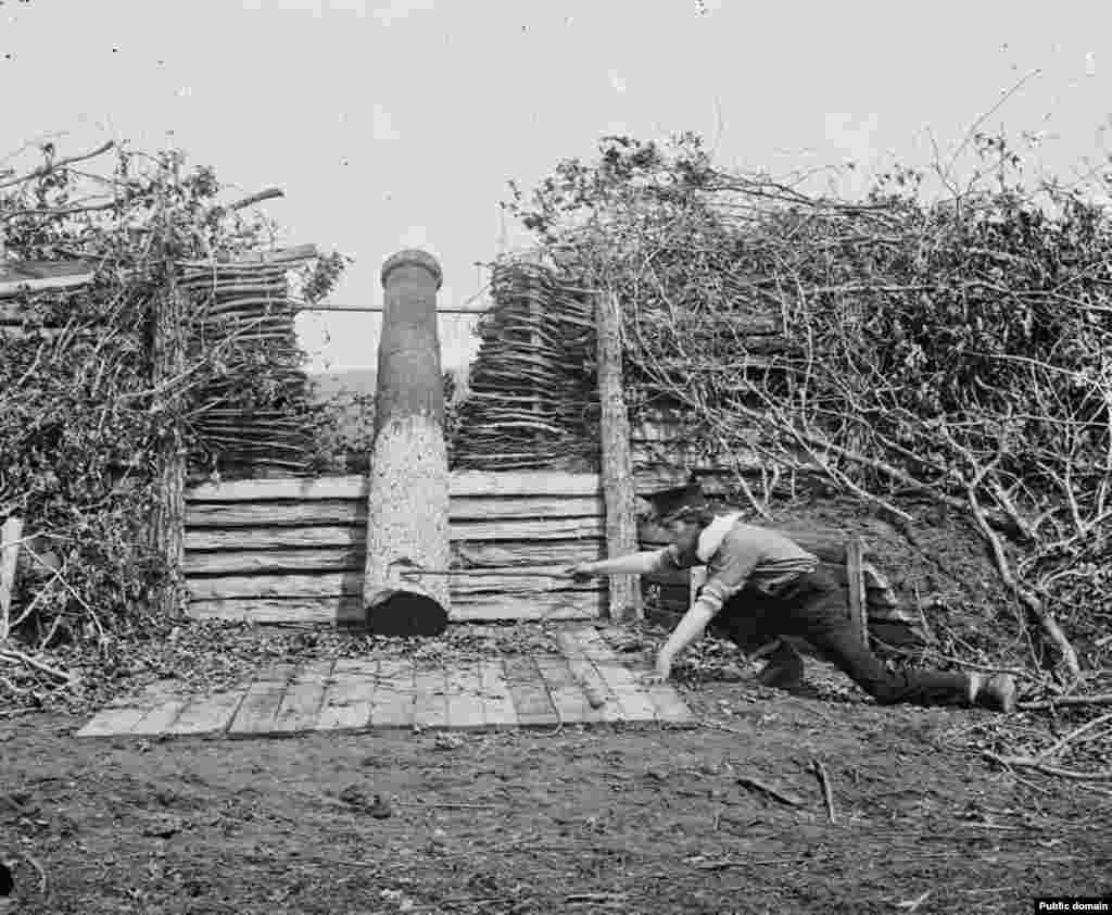 A man pretends to fire a Quaker gun. The dummy weapons were sometimes used to buy a retreating army time as they hauled away their real cannons under cover of darkness. Quaker guns were named after a Christian sect devoted to nonviolence.