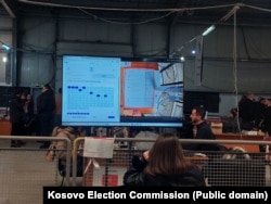Në një ekran shfaqet një fletëvotim, teksa komisionerët numërojnë votat për zgjedhjet e parakohshme parlamentare të 28 dhjetorit.