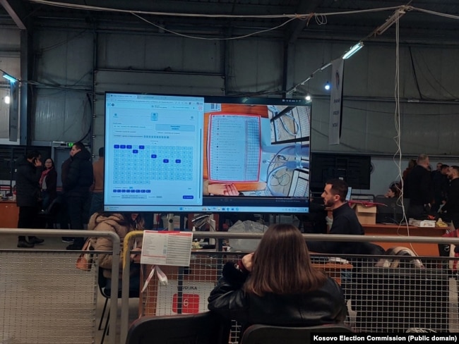 Në një ekran shfaqet një fletëvotim, teksa komisionerët numërojnë votat për zgjedhjet e parakohshme parlamentare të 28 dhjetorit.