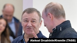 Russian President Vladimir Putin (right) speaks with Arkady Rotenberg as they attend the opening ceremony for a bridge linking the annexed Crimean Peninsula to Russia, in Kerch, in May 2018.