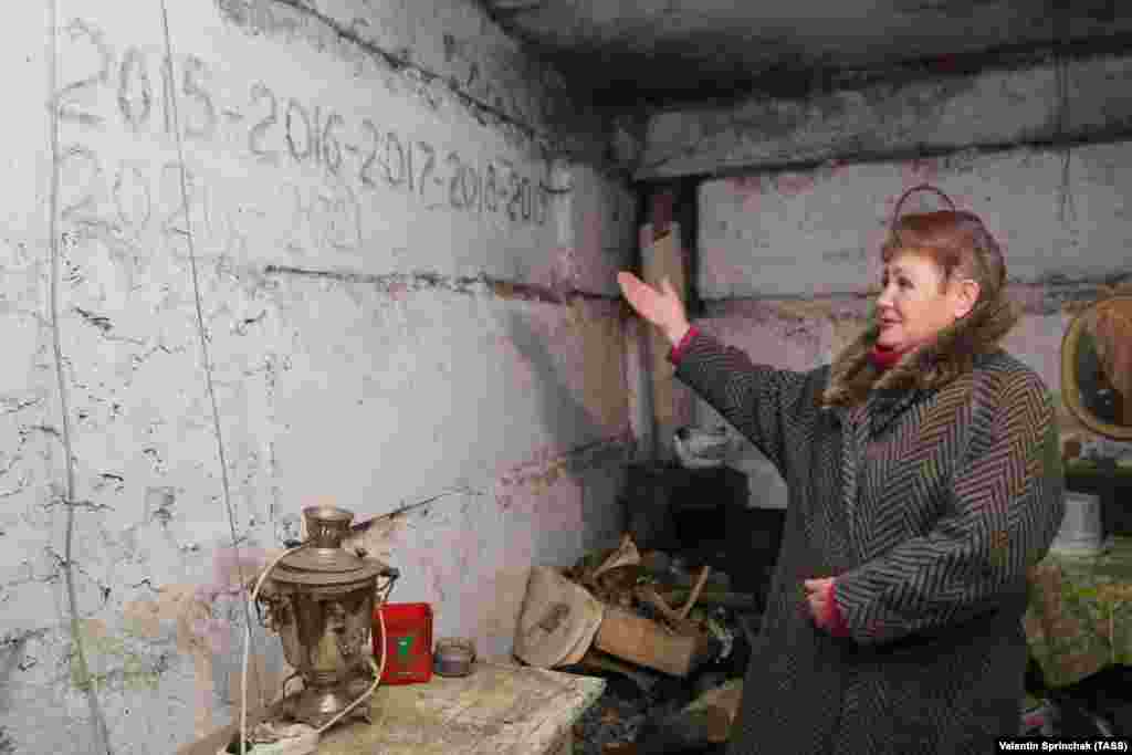 Egy nő mutatja az óvóhely falára írt évszámokat, amikor itt kellett a helyieknek szilveszterezniük. &nbsp;