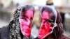 Afghan women in Kabul in March 2016 wear masks depicting Farkhunda Malikzada, who was killed by a mob a year earlier.