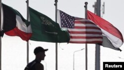 Un bărbat merge lângă steagurile kuweitian, egiptean, saudit și american înaintea unui summit internațional privind Gaza, ce are loc în stațiunea Sharm el-Sheikh din Egipt.