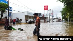 Люди идут по затопленной улице в Поса-Рика-де-Идальго, штат Веракрус, Мексика, 10 октября 2025 года