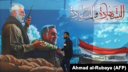 Një person në Irak kalon pranë një murali ku janë portretet e Qasem Soleimanit dhe Abu Mahdi al-Muhandis të vrarë në sulmin me dron të SHBA-së.
