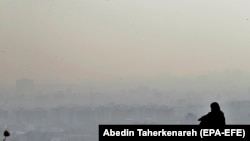 Девушка наблюдает за смогом над Тегераном с горы Дарабад, к северу от столицы Ирана, 16 октября 2020